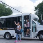 Cathy Wu waves to members of Brenau's student services department, not pictured, while Crystal Wang gets off the bus for the first time on campus.