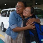 Daisy Qiu gets a hug from Dr. Crystal Toombs, associate provost for adult and graduate studies, before boarding a bus to leave the airport.