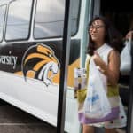 Lisa Wang walks off the bus with items she bought for her residence.